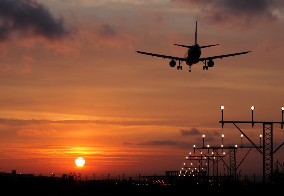 Aeroplane landing in a sunset over runway approach lights